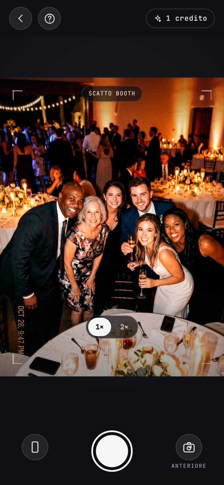 The AI photobooth in the app: a camera of its own, open on a group of guests leaning in at a candlelit reception, with a “booth shot” badge across the viewfinder, a help button top-left and the booth credits left top-right