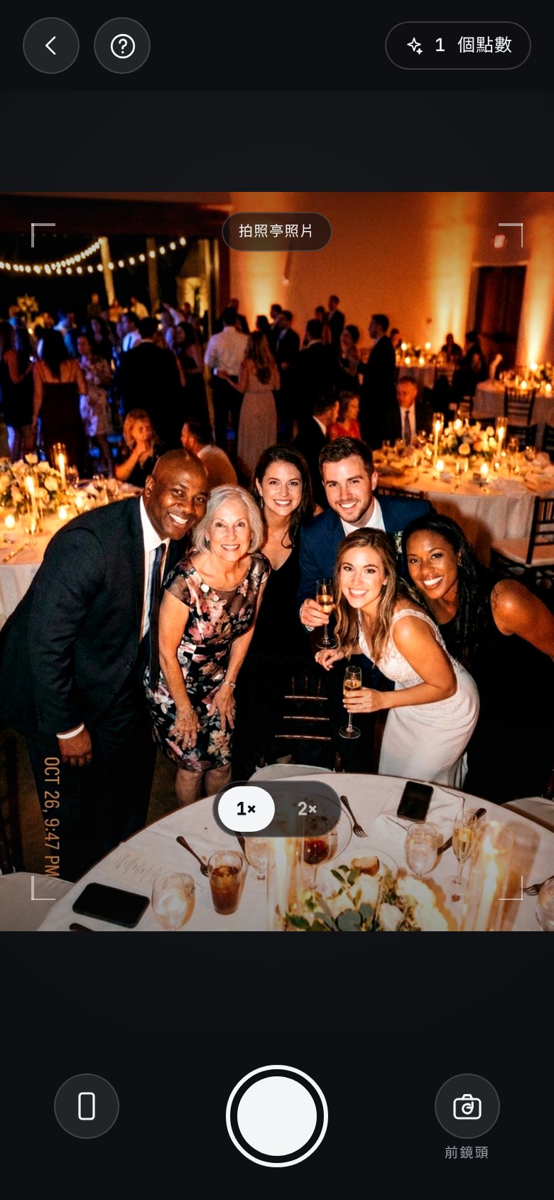 The AI photobooth in the app: a camera of its own, open on a group of guests leaning in at a candlelit reception, with a “booth shot” badge across the viewfinder, a help button top-left and the booth credits left top-right